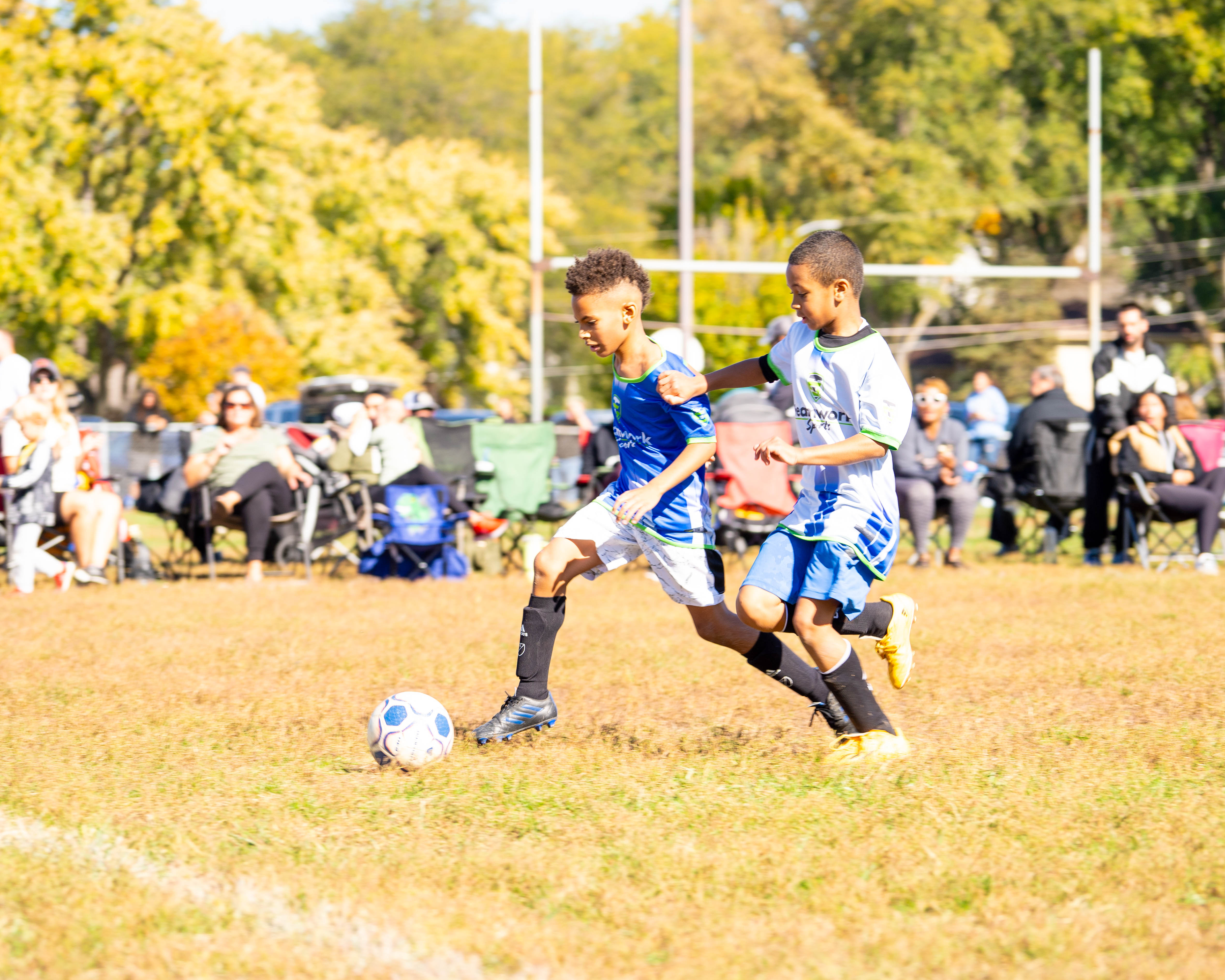 Two young players competing for the ball during a Teamwork Sports soccer game