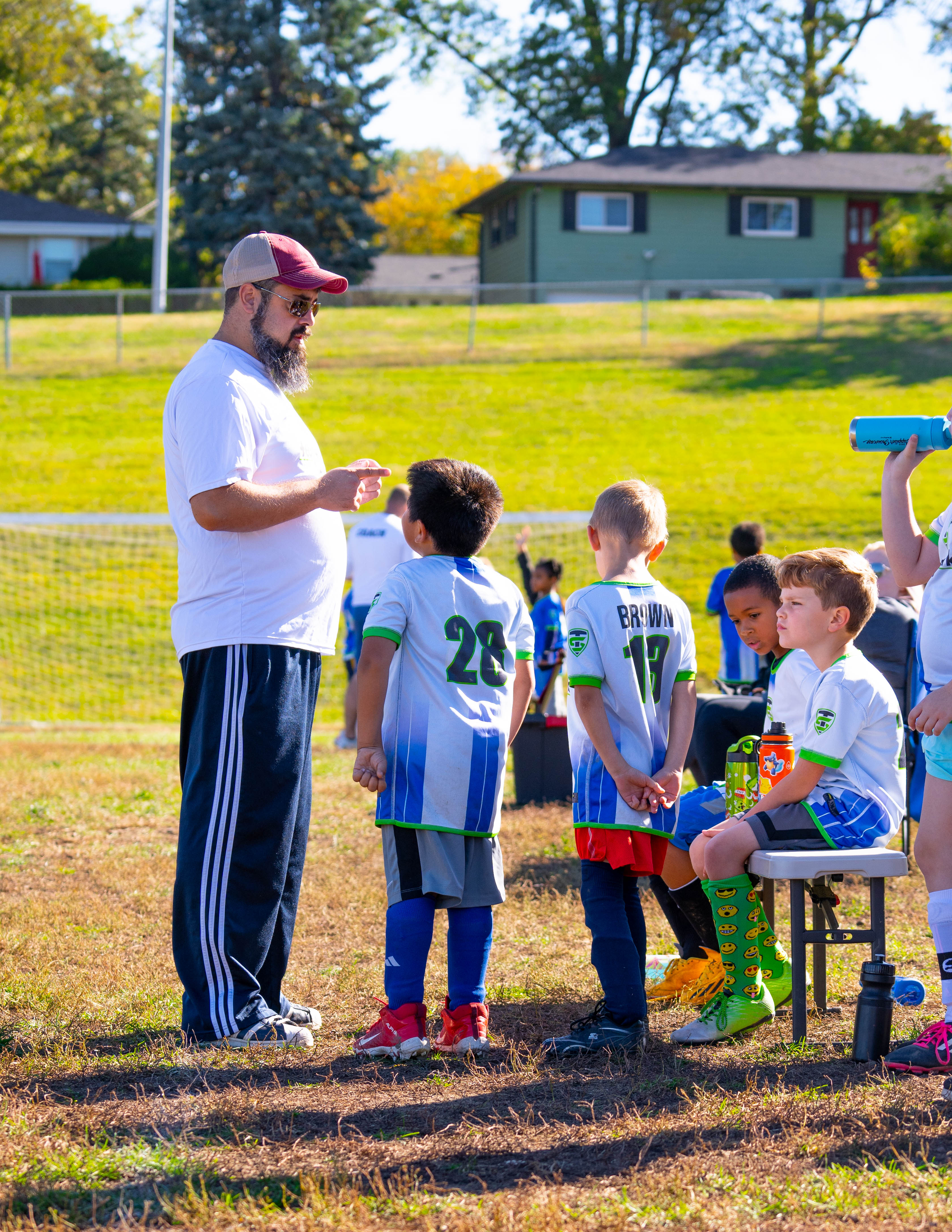 A coach giving instructions to his young team on the sideline